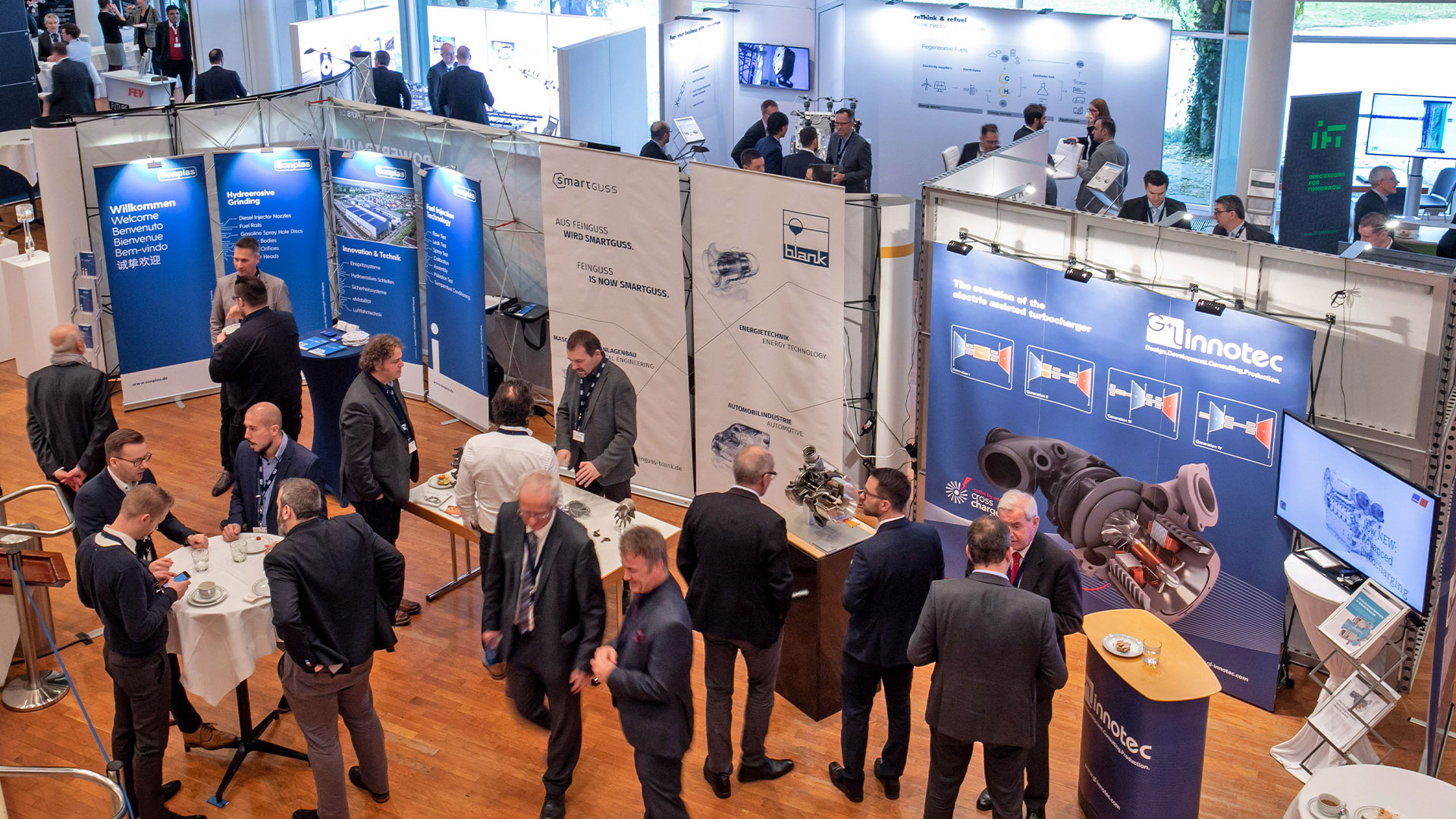 Gruppen von Konferenzteilnehmern unterhalten sich im Ausstellungsbereich.